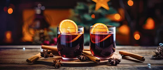 Fotobehang dos copas de vino caliente de navidad sobre mesa decorada con naranja y canela, con fondo desenfocado de decoración navideña © Helena GARCIA