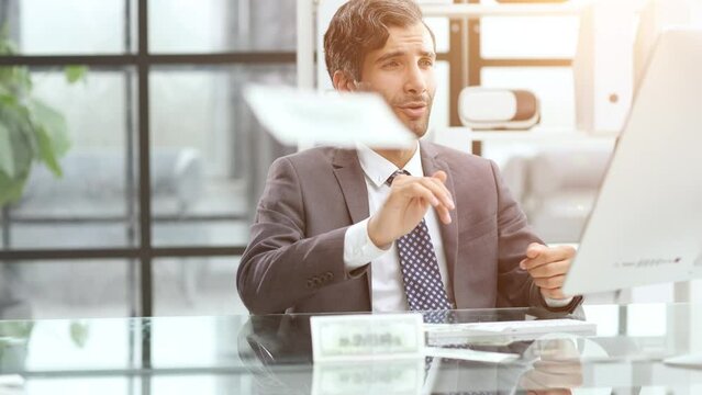 Surprised businessman holding banknote near computer in office