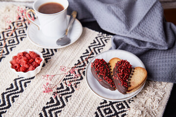 Heart shaped cookies with raspberry taste and cup of coffee. Romantic lagom holiday food background.