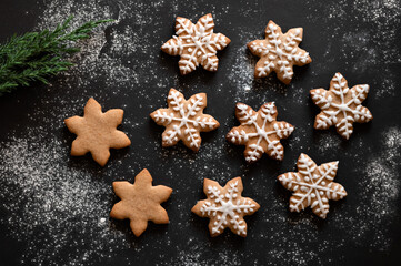 Christmas gingersnap, traditional ginger cookie in star shape decorated with sugar icing on black table background with flour. Winter holiday homemade family treat