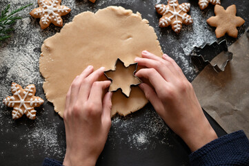 Rolled dough on table with flour, hands holding cookie cutter with star shape, baking traditional...