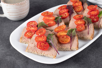 Homemade sandwiches with turkey pate and cherry tomatoes, also a cup of coffee on gray background