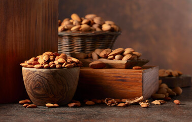 Almonds in wooden bowl on a brown vintage background.