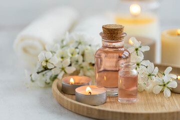 Obraz na płótnie Canvas Burning candles, spa setting, essential oils, organic pure aromatic ingredients, atmosphere of relax. Aromatherapy, cozy home decor concept. Perfumery bottles, elegant composition with spring flowers