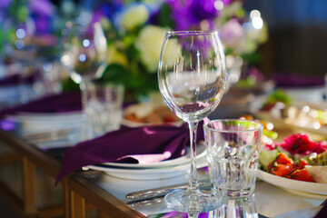 Beautiful festive table setting with flowers and purple napkins. 