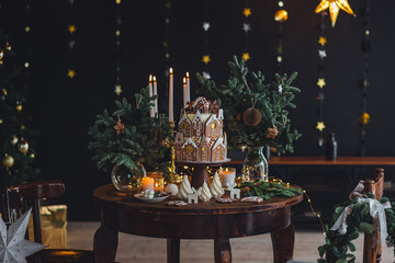 Elegant beautiful handmade gingerbread cookies house with white sugar frosting. Cute magic Christmas village, holiday aesthetics. Cozy home atmosphere, holiday family time. Interior decor, candles