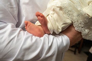 a man holds a small child in his arms, before baptism. The legs of a small child