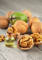 Walnut kernels, whole walnuts and bottles of essential nut oil on rustic wooden table. Healthy walnuts.