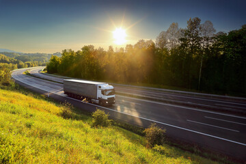 Large Transportation Truck on a highway road through the countryside at sunset