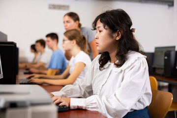 Fototapeta premium Concentrated Asian female student using PC and studying computer science in the classroom