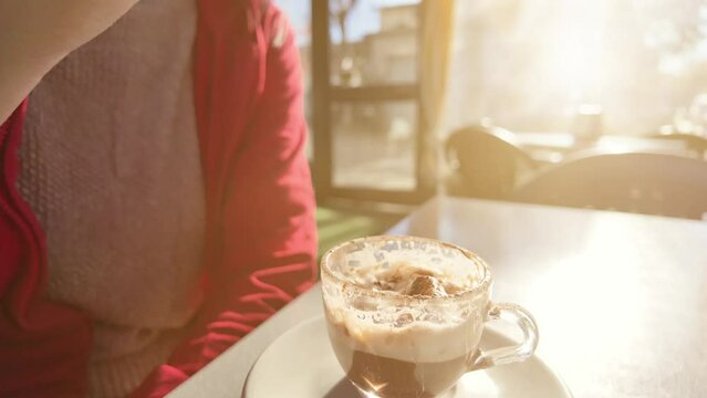 SLOW MOTION: Chic woman savoring a warm cappuccino in a quaint Italian cafe as dawn breaks. The rich aroma of the coffee blends with the fresh morning air, invigorating her senses.