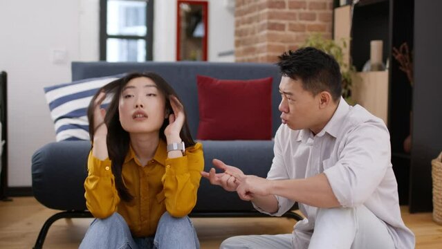 Emotional asian middle aged man gesturing and shouting at his annoyed wife, chinese couple having quarrel at home