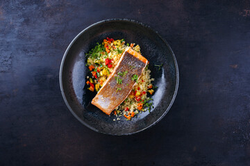 Traditional Mediterranean salmon fish fillet with vegetable cuscus served as top view on a design...