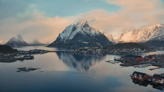 Aerial view of snowy rocks, islands with rorbuer, sea, bridge, mountains, road, purple cloudy sky at sunrise in winter. Top drone view of rorbu in Hamnoy village, Lofoten islands, Norway. Dramatic
