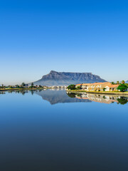 Fototapeta na wymiar Vertical shot of the table mountain and its reflection in the woodbridge island lagoon during a clear day with blue sky, Cape Town South Africa
