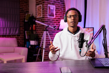 Content creator broadcasting live on streaming platform from vibrant neon lights home studio using...