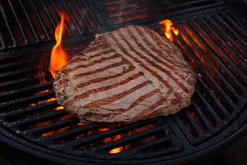 Traditional American barbecue flanksteak steak as close-up on a charcoal grill with fire