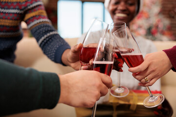 Cheerful colleagues holding beverage glasses and clinking while celebrating winter seasonal holiday...