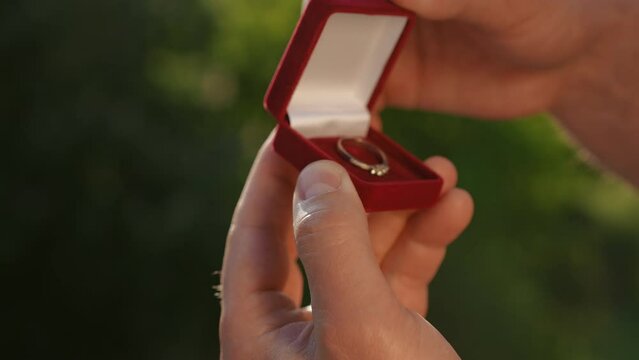 Close-up: a velvet box with a ring inside, which is opened by a man with his hands