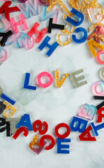 Acrylic letters, word love amid acrylic letters scattered randomly on light surface, selective focus.
