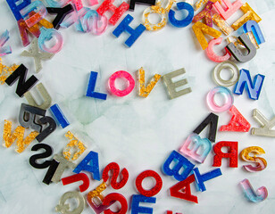 Acrylic letters, word love amid acrylic letters scattered randomly on light surface, selective...