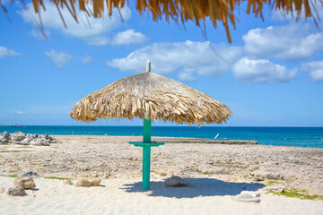 Thatched hut on a stretch of beach in Aruba overlooking the Caribbean Sea. Beautiful Caribbean summer seascape scene. Space for text. 