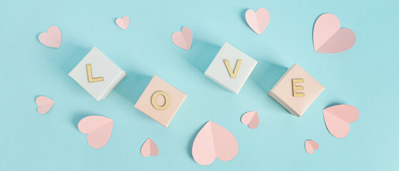 Paper hearts and gift boxes with word LOVE on light blue background. Valentine's Day celebration