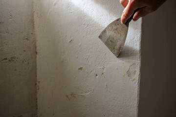 preparing the wall with a spatula to paint it