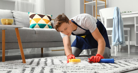 Handsome man cleaning carpet with sponge at home