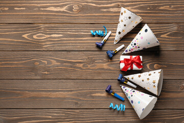 Composition with party hats, whistles, gift box and serpentine on wooden background