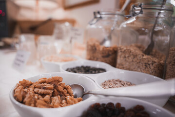 A variety of cereal, nuts, and granola in bowls and jars arranged in a horizontal line. Beautiful and delicious breakfast setup in Venice, Italy.