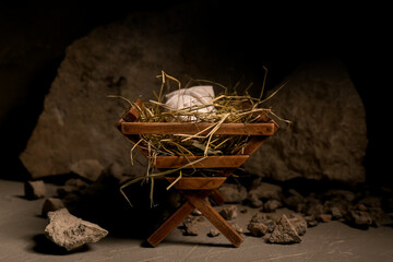 Manger with baby, hay and stones on dark table