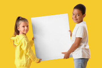 Cute little children with blank poster on yellow background