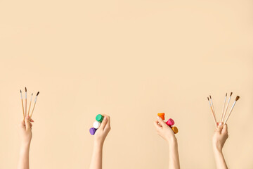 Female hands with artist's supplies on beige background