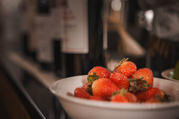A close-up of vibrant red strawberries in a bowl next to a bottle of wine on a counter. This Venice collection features popular places, luxury interiors, and real Venetian style.