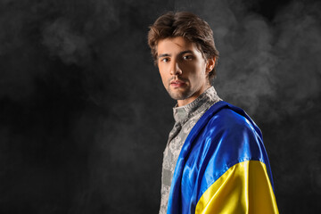 Young male soldier with flag of Ukraine on black background