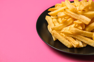 Plate with golden french fries on pink background, closeup