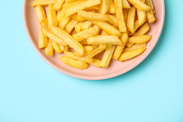 Plate with golden french fries on blue background