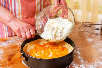 Chef pours batter into pan to prepare fruit cheesecake.