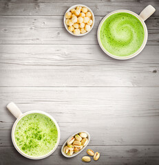 Pair of two matcha lattes with pistachos filberts and nuts on a table top