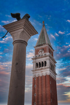Historic clock tower and lion statue in Piazza San Marco, Venice, Italy. Daytime photo with no specific landmarks in the background. Architectural style and historical significance not provided.