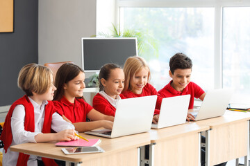 Little children studying with laptops at school computer lab
