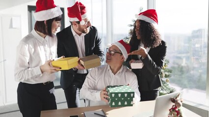 Multiethnic team of people giving presents during christmas festivity, celebrating winter holiday in startup office. Coworkers exchanging xmas gifts, seasonal festive decorations. - Powered by Adobe