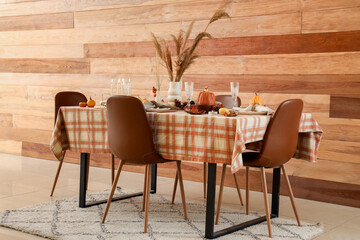 Autumn table setting with pumpkins, burning candles and pampas grass in dining room