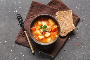 Bowl with delicious beef stew and bread on black background