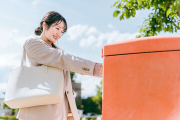 郵便ポストに手紙を入れる女性（郵送・発送・申し込み）
