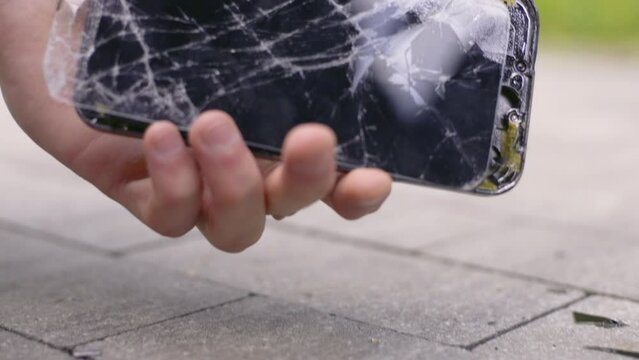 Crash smartphone on pavement and man picks it up holding a smartphone with broken screen in hand, Super slow motion footage 4K UHD B-Roll