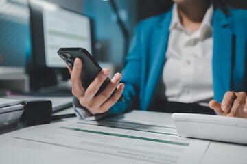 Female accountant working about financial with calculator at her office, Savings, Finances and economy concept, Beautiful Asian businesswoman analyzes charts using laptop calculator at the office.