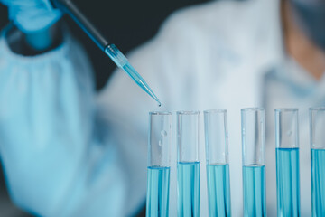 Young scientists in sterile clothing and safety goggles sitting at table conducting research...