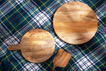 View of wooden chopping boards on a plaid blanket laid out for a summer picnic, flat lay. The concept of summer outdoor recreation on the weekend